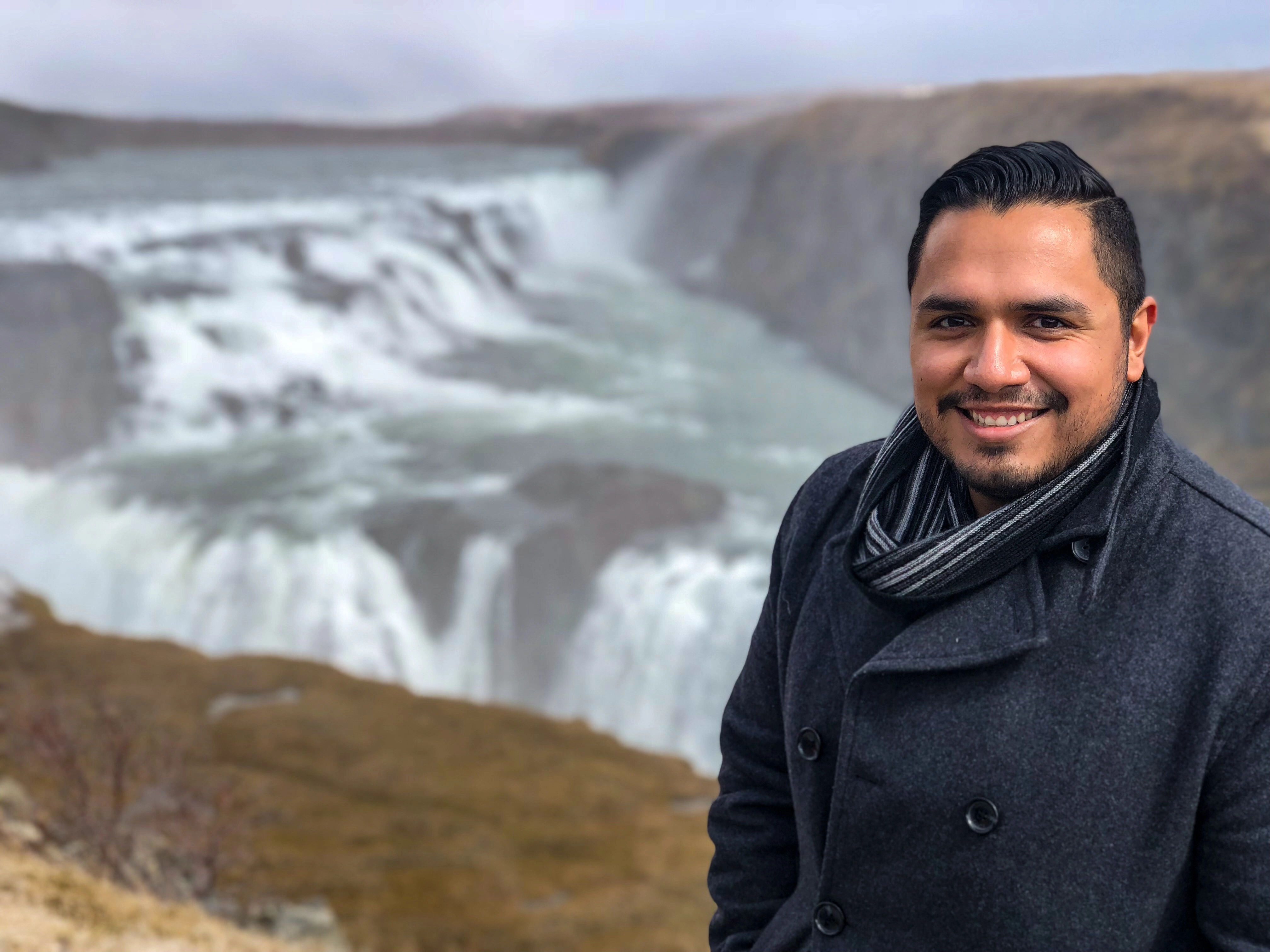 Vincent smiling beside a broad waterfall